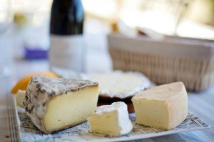 Photo of a cheese platter with a bottle of red wine in the background